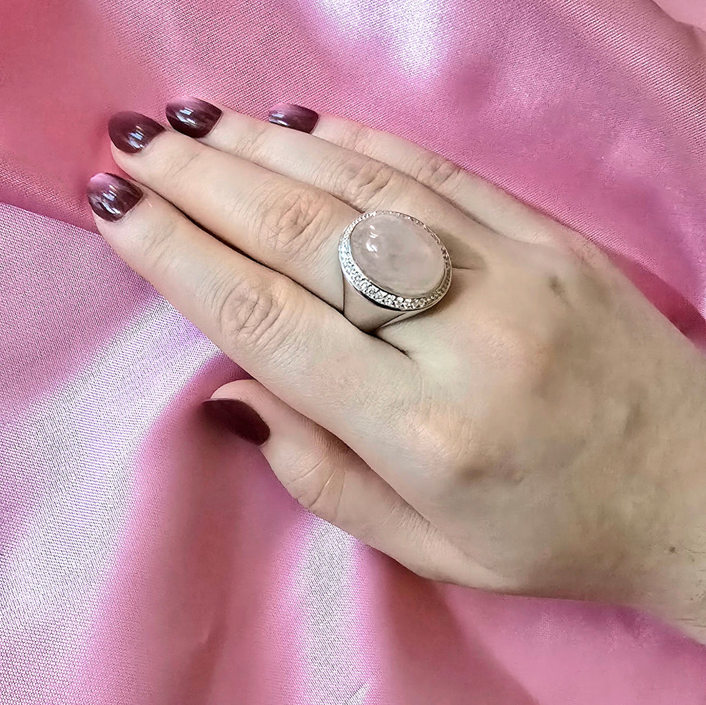 Hand mit Ring in Silber und großem Rosenquarzstein in ovaler Form