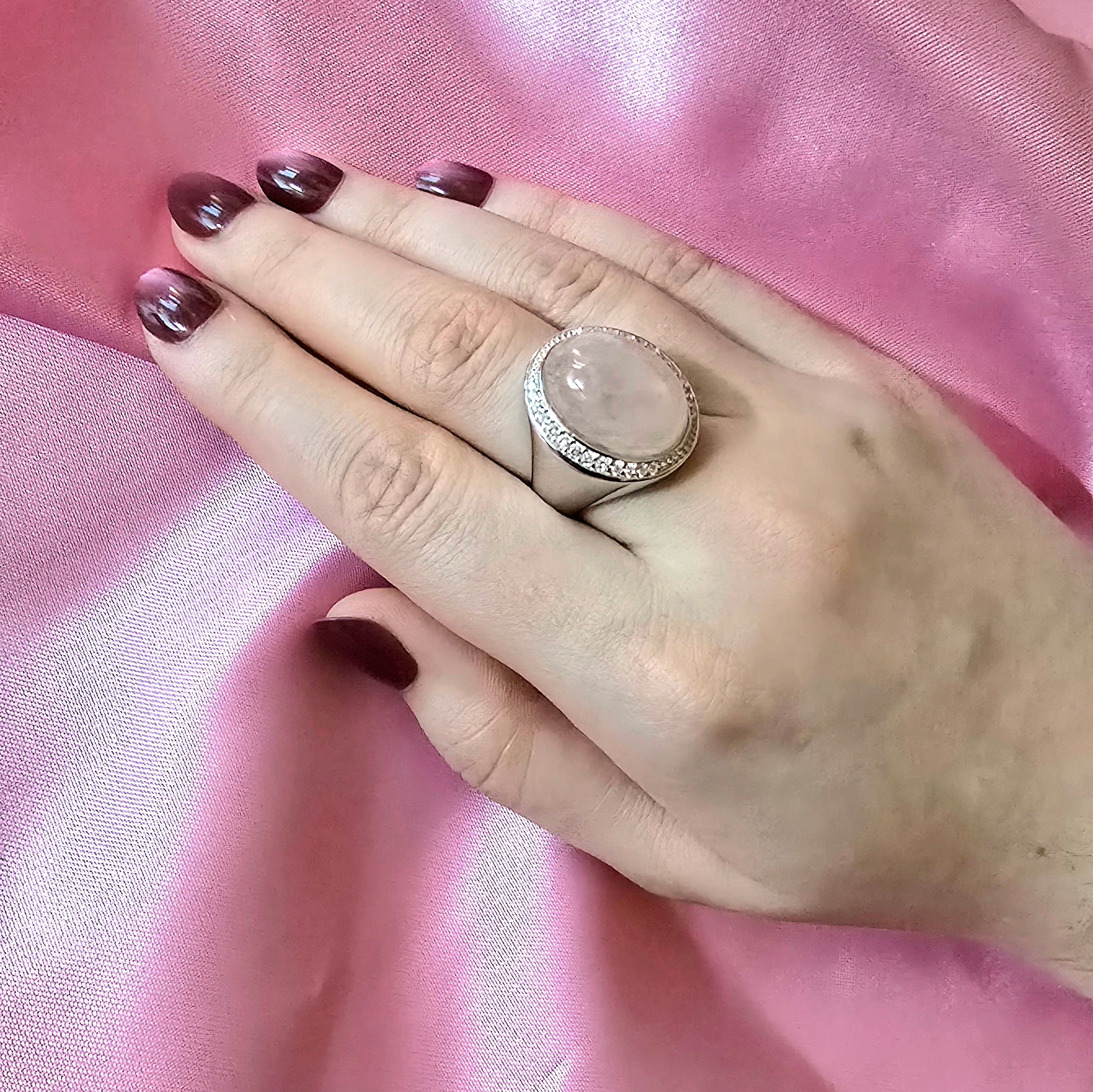 Hand mit Ring in Silber und großem Rosenquarzstein in ovaler Form